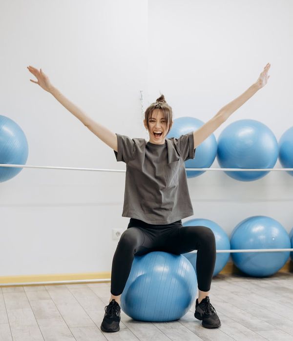Woman smiling and stretching in a bright, airy room, feeling energetic.